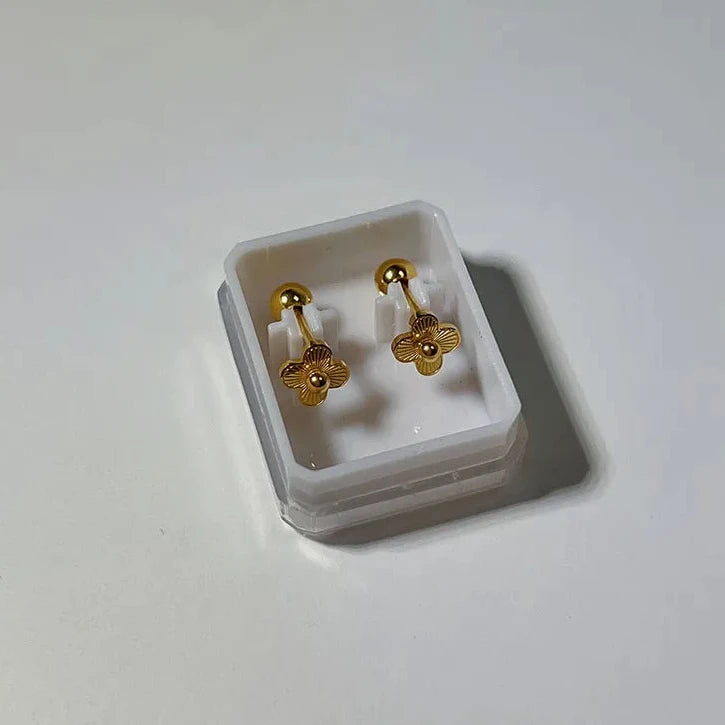 Gold earrings in a white box on a light gray background