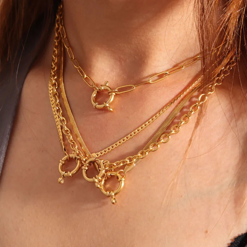 Close-up of a person wearing multiple gold necklaces with intricate designs.