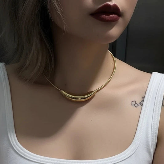 Person wearing a gold necklace with a dark background
