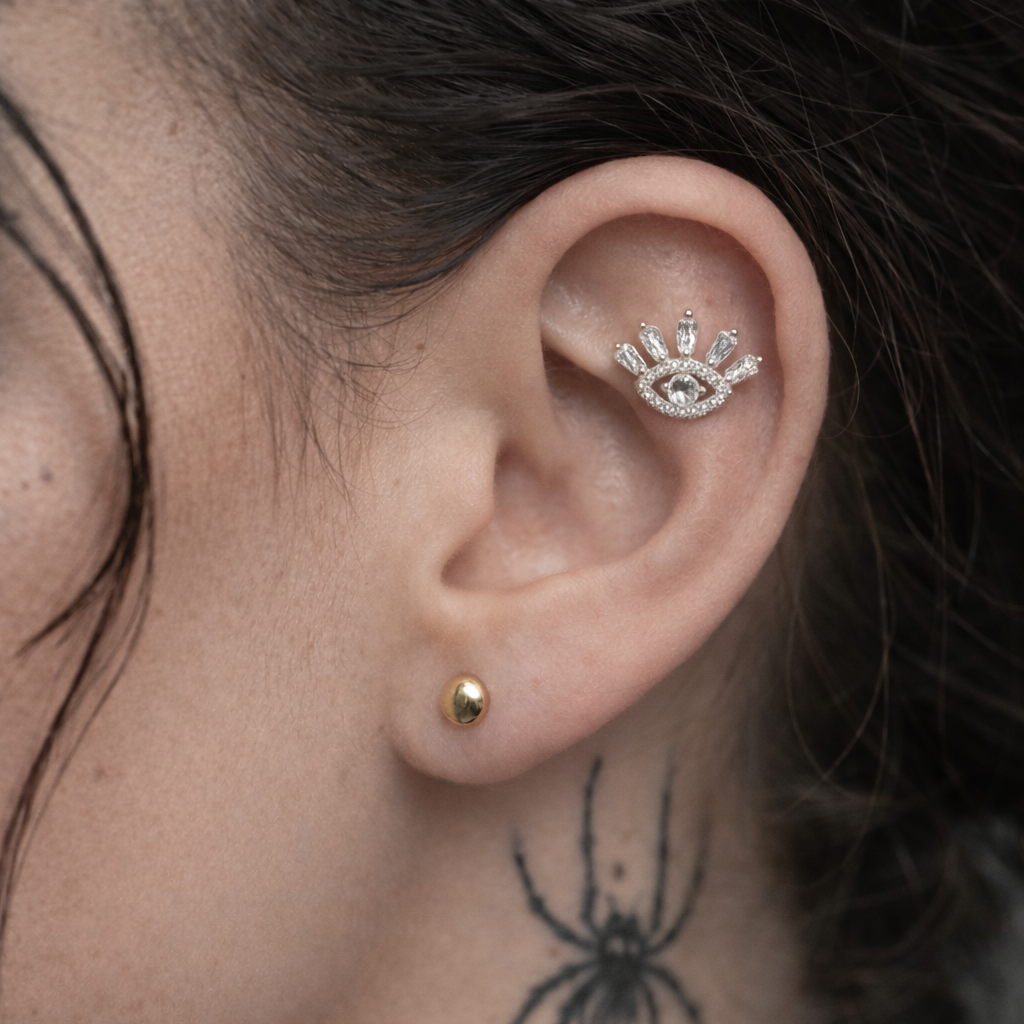 Close-up of an ear with earrings, a spider tattoo on the neck, and a chain necklace.