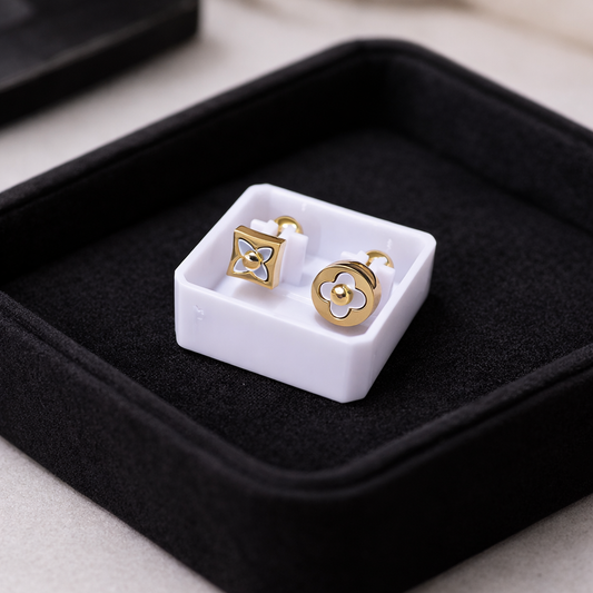 Gold earrings on a white square in a black jewelry box