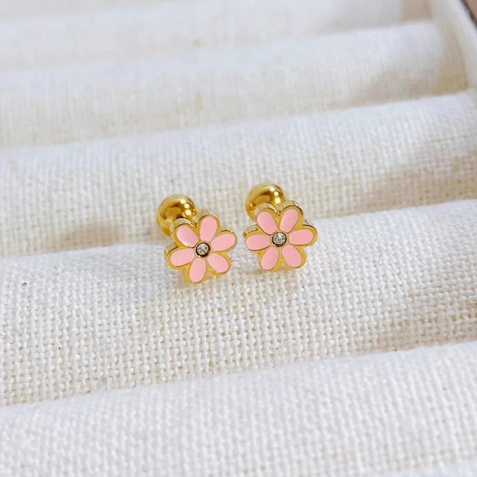 Pair of pink flower earrings with gold accents on a white fabric background