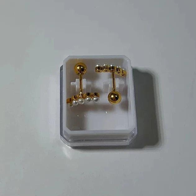 Gold and pearl earrings in a clear plastic display case on a white background