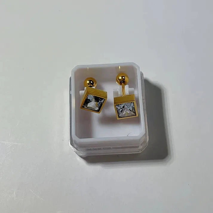 Gold square earrings with clear stones in a clear display case on a white background