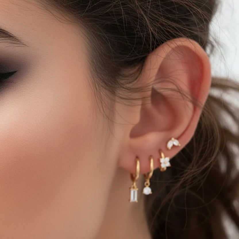 Close-up of an ear wearing gold hoop earrings with diamond-like stones.
