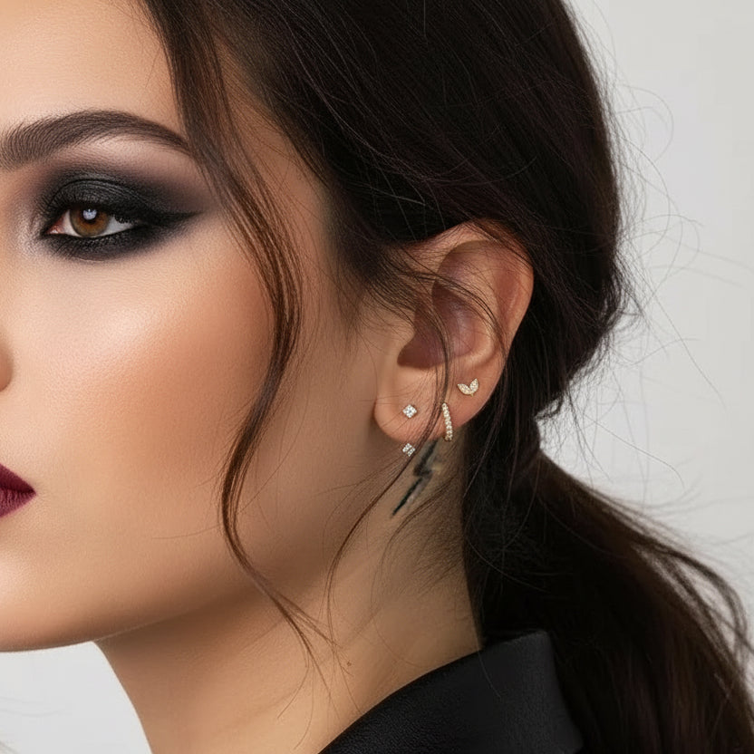 Close-up of an ear wearing multiple gold earrings with a blurred background