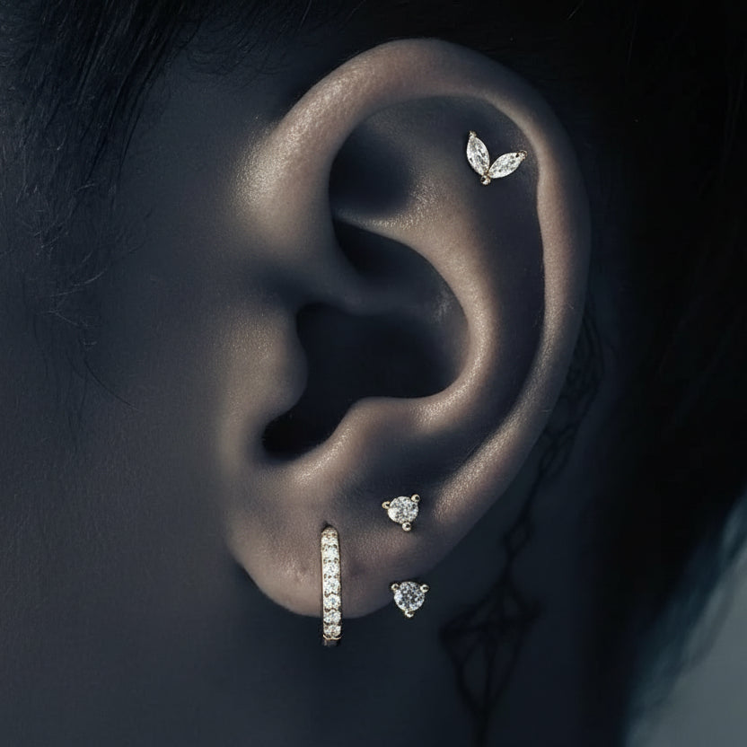 Close-up of an ear wearing multiple diamond earrings with a dark background