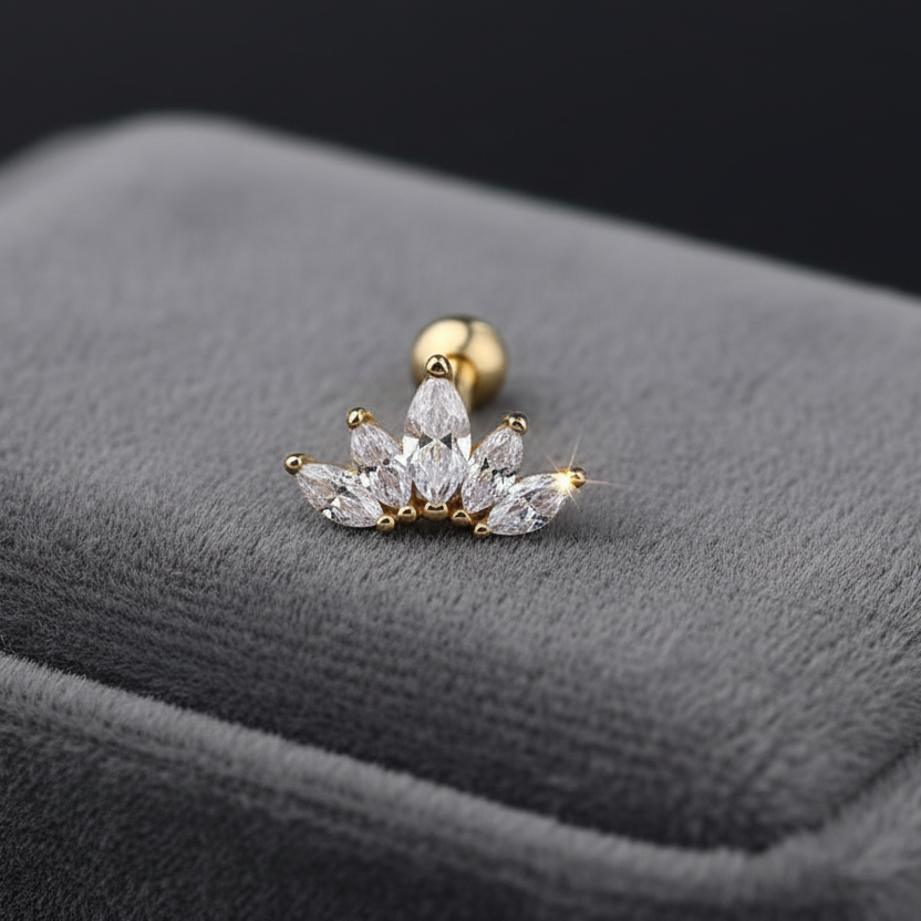 Gold and diamond earring on a gray cushion with a black background